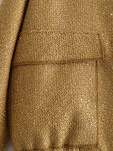 Close-up of gold sequin tweed fabric and pocket flap detail on the women jacket