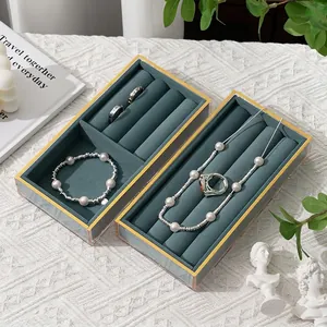 Elegant gold-framed acrylic jewelry box with dark green velvet lining and multiple slots