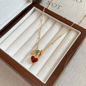 Detail of an 18k gold plated necklace with a red heart pendant on a wooden jewelry box