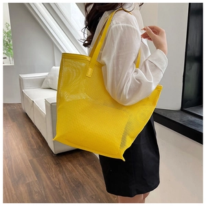 Detailed view of bright yellow mesh tote bag with fine PVC texture and shoulder strap