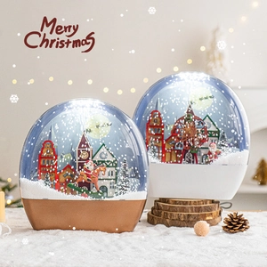 Illuminated Christmas snow globe scene with Santa and miniature houses on snowy base