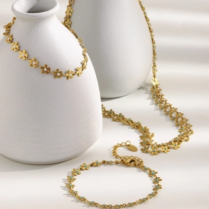 Detail of 18K gold plated necklace and bracelet with white and blue flower enamel motifs