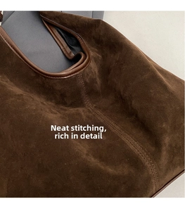 Detailed view of dark brown suede tote bag featuring vertical stitching and leather piping