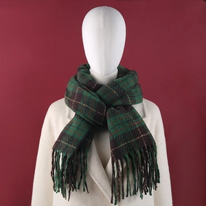 Detail of green and brown plaid knit scarf with tassels on white mannequin model