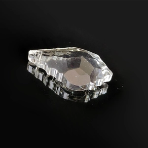 Macro shot of faceted clear glass leaf pendant with light reflection on a black background