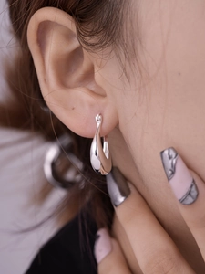 Detailed close-up of a model wearing high-polished silver hollow geometric U-shaped hoop earrings
