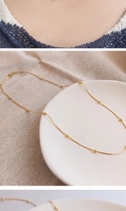 Detailed macro view of 18K gold snake chain necklace with beads on linen cloth