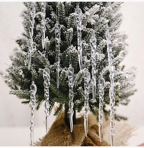 Detailed view of clear acrylic icicle ornaments hanging on a snowy Christmas tree branch