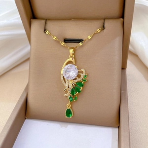Macro view of gold peacock pendant featuring a large white zircon and green gemstones