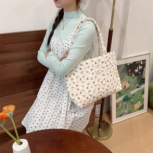Detailed shot of white quilted tote bag featuring floral patterns and bear embroidery