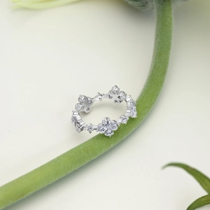 Detail of silver S925 floral ring with white zircons on a green plant stem