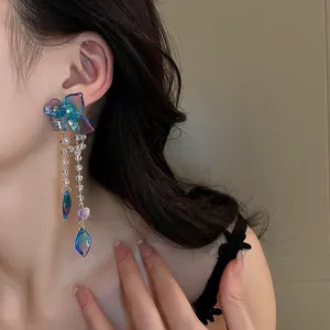 Macro detail of long tassel earrings with blue-purple gradient flower charms and beads