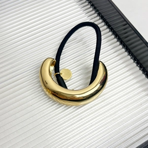 Close-up of a minimalist gold C-shaped metal buckle on a black elastic hair tie
