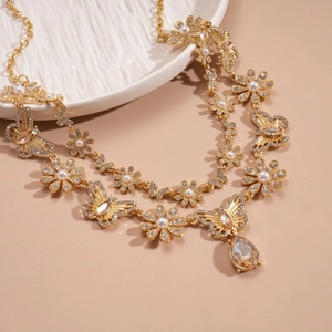 Detail of double-layer gold necklace with crystal teardrop, pearls and hollow butterflies