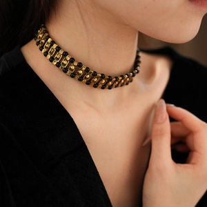 Detail of vintage black and gold beaded choker necklace worn on model's neckline