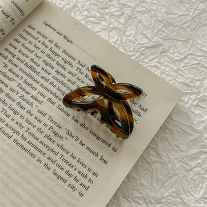 Detail of tortoise shell acetate bow hair claw clip placed on an open vintage book
