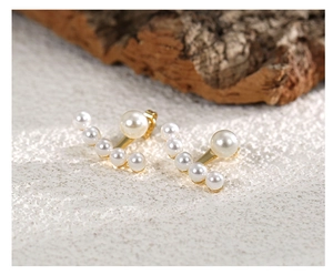 Detailed view of elegant gold pearl earrings with a floating bead design on a natural base