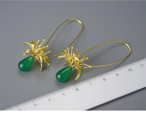 Detailed view of silver flower earrings with green chalcedony beads and measuring scale