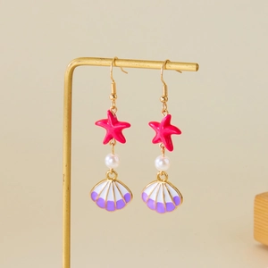 Creative starfish and seashell drop earrings with pearls on a gold metal jewelry stand