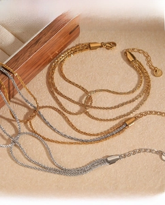 Macro detail of layered PVD gold stainless steel bracelets with lobster clasp and chain