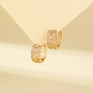 Close-up of golden geometric hoop earrings with hollow patterns and zircon inlay
