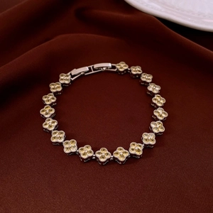 Detailed view of silver clover bracelet with yellow stones on red satin background