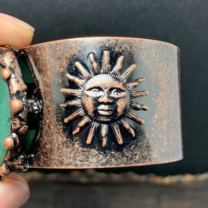 Detailansicht der Vintage Kupfermanschette mit Sonnengott Relief und grünem Edelstein