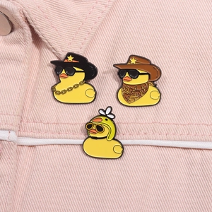 Vue détaillée de trois épingles en émail de canards jaunes sur jean rose