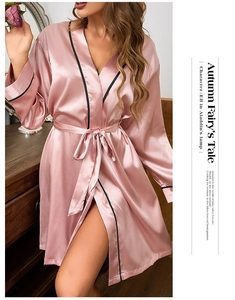 Detail of pink satin bathrobe with black contrast piping and elegant silk-like texture