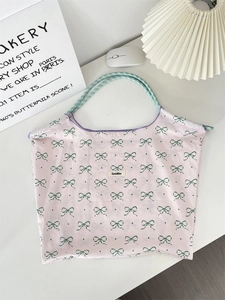 Close-up of floral tote bag with green bow patterns and woven rope handles