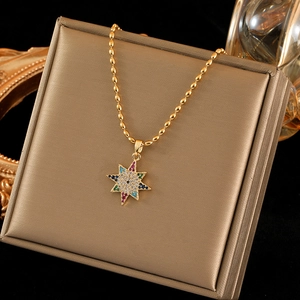 Golden star pendant necklace with colorful zircon stones on a brushed metal jewelry box