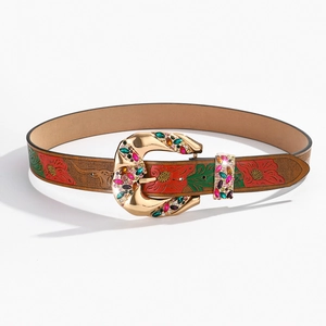 Close-up of brown leather belt with floral embossing and gold rhinestone buckle