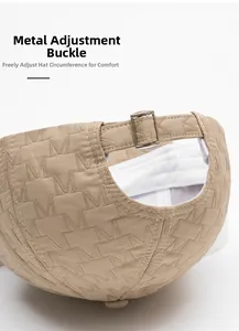 Detail of beige baseball cap with metal adjustment buckle and textured M embroidery