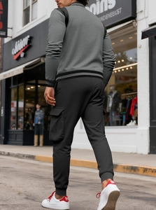 Vista posteriore di uomo in cardigan grigio e pantaloni cargo neri con tasche multiuso