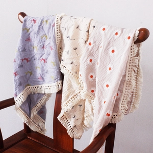 Detail of baby swaddle blankets with tassel edges featuring floral and reindeer prints