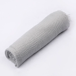 Macro detail of grey crinkle cotton linen scarf showing textured gauze and raw fringe edges