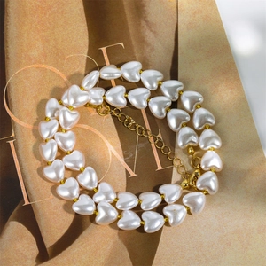 Detail of elegant double-layered pearl necklace with golden heart beads and lobster clasp