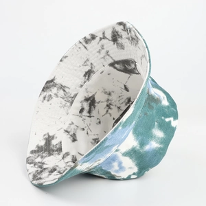 Detail of reversible tie-dye bucket hat showing blue-green ink patterns and cotton texture