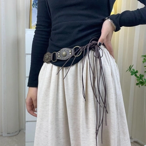 Detail of dark brown leather Y2K belt featuring vintage metal discs and fringe ties