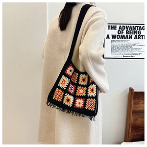 Detail of granny square crochet bag in black with colorful patterns and fringe