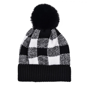 Détail du bonnet en tricot à carreaux noir et blanc avec un pompon en fausse fourrure douce