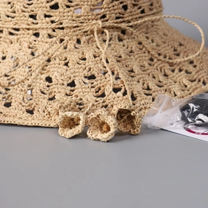 Détail d'un chapeau de paille au crochet évidé avec fleurs tissées et cordon réglable