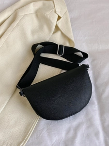 Flat lay of black lychee leather crescent bag with wide strap on linen blazer