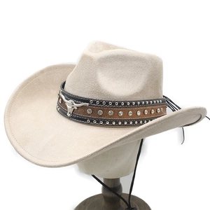 Detail of beige suede cowboy hat featuring bull head emblem and rhinestone decoration