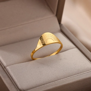 Macro view of 18K gold stainless steel ring with sun engraving in a beige box
