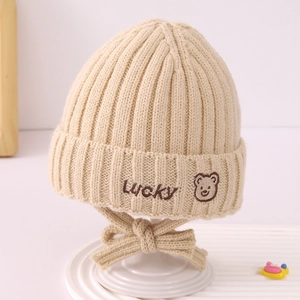 Close-up of beige knit baby hat featuring Lucky embroidery and teddy bear detail