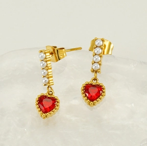 Detail of vintage gold heart earrings with red zircon and pearls on crystal stand