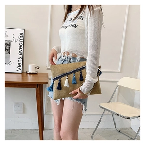 Ethnic style envelope clutch bag featuring blue tassels and woven wristlet detail
