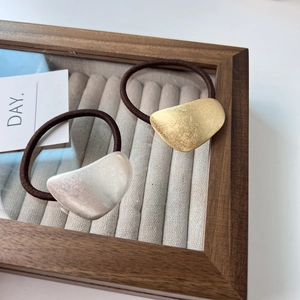 Detail of gold and silver geometric metal hair ties on velvet jewelry display