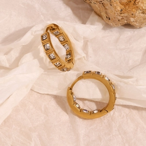 Close-up of 18K gold plated hoop earrings with square cubic zirconia on beige paper